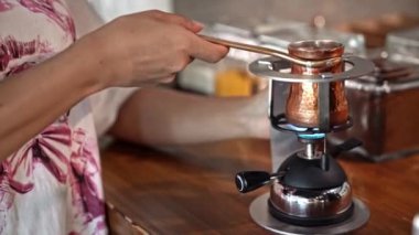 Portatif sobada bakır kahve yapmak, geleneksel demleme metodu, el yapımı aromatik içecek hazırlama, rahat mutfak sahnesi, sıcak kafe atmosferi, Türkiye, Alanya, 16 Temmuz 2024