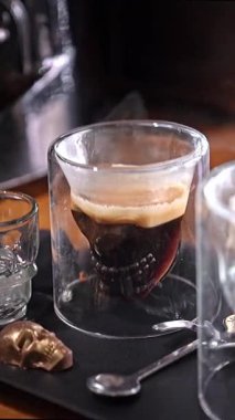 Kafatası şeklindeki camda buharlı kahve, gizem ve Cadılar Bayramı atmosferini çağrıştırıyor, gotik koyu tonlar, tehlike işareti, yoğunluğu sembolize eden, cesaret, kafein ritüeli, Türkiye, Alanya, 16 Temmuz 2024..