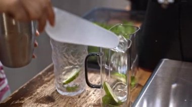 Barmen kireç hazırlıyor, buz dolduruyor, taze malzemeleri karıştırıyor, yaz atmosferini yakalıyor, narenciye kokteyli hazırlıyor, soğuk içecek hazırlıyor, cam dolduruyor, su dolduruyor, bar atmosferine giriyor..