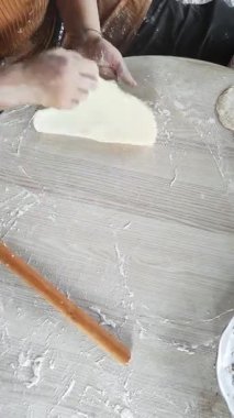 Sıcak bir mutfakta, yetenekli bir kadın ahşap bir oklava ile hamuru ustalıkla çıkarıp leziz gözleme için mükemmel bir temel oluşturuyor..