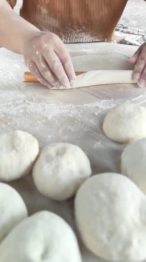 Sıcak ve davetkar bir mutfakta, bir kadın ahşap bir oklava kullanarak ustalıkla taze hamur çıkarır. Ustalıkla hamuru düzleştirirken un, lezzetli gözleme için hazırlanıyor..