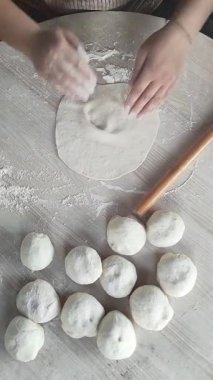 Sıcak bir mutfakta, bir kadın ahşap bir iğneyle ustalıkla hamuru yuvarlar, güzel hareketlerle unu birleştirir..