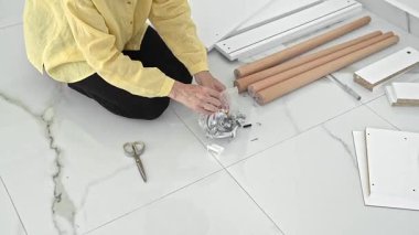 Bir kadın yeni mobilyalarını dikkatlice yerleştirirken heyecan havayı dolduruyor. Tüm parçaları dizer ve aksesuarları kontrol eder. Yeni dairesinde eğlenceli bir kendiliğinden montaj deneyimi için hazırdır..