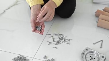 Mobilya donanımlarının yeni detaylarını merak eden bir kadın kendi kendine montaj için eşyaları dikkatle kontrol ediyor. O vida ve aksesuarlar organize eder, eğlenceli bir yeni ev projesine hazırlanır..