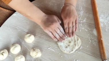 Eller ahşap bir yüzey üzerinde özenle çalışır, yumuşak hamuru mükemmel mermilere dönüştürür. Un tozu etrafa yayılır fırının kokusu havayı doldurur ve mutfakta sıcak bir atmosfer yaratır..