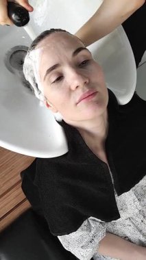 Güzellik salonunda sakin bir anın tadını çıkar. Müşterinin saçlarını nazikçe yıkarken. Sakinleştirici ortam deneyimi güçlendirir, rahatlamayı ve gençleşmeyi teşvik eder..