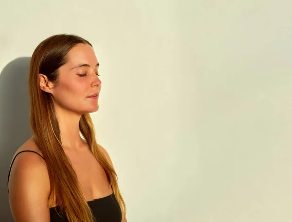 stock image portrait young caucasian woman meditating with closed eyes in studio with evening light	