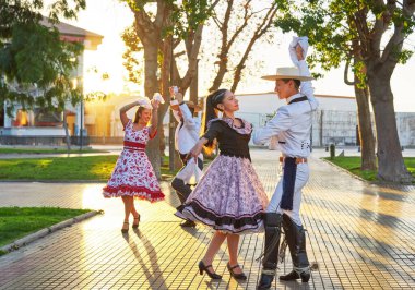 group of two Latin American couples of huaso dancing cueca in the town square at sunset in La Serena clipart