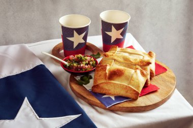 Şili Empanadas de Pino ve Pebre 'nin ahşap tepside ve Şili bayrağıyla dolu gözlüklü, ulusal bayram konsepti
