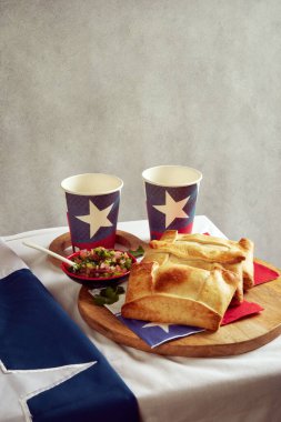 Şili Empanadas de Pino ve Pebre 'nin ahşap tepside ve Şili bayrağıyla dolu gözlüklü, ulusal bayram konsepti