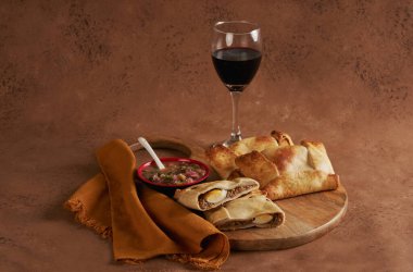 Durgun hayat Empanadas de Pino, ahşap mutfak tahtasında peber ve bir bardak şarap