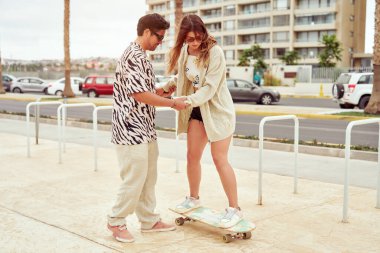 Neşeli heteroseksüel çift arka planda Pasifik Okyanusu varken sokakta beşlik çakıyor.