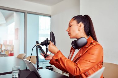 Podcaster stüdyosunda ses içeriği kaydetmek için ekipman hazırlıyor