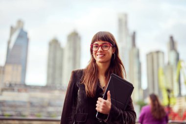 Portre başarılı genç iş kadını şehir ortamında dijital tablet tutuyor