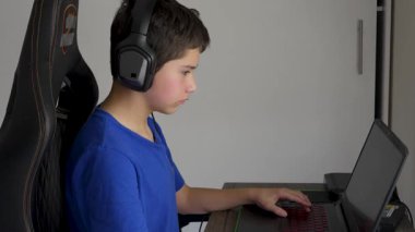 çocuk evde bilgisayar ve kulaklık kullanarak oyun oynuyor.