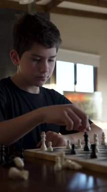 Evde satranç oynayan konsantre çocuk.