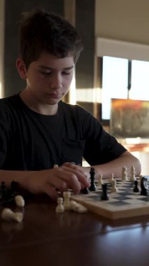Evde satranç oynayan konsantre çocuk.