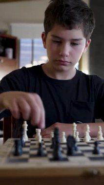 Evde satranç oynayan konsantre çocuk.