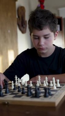 Evde satranç oynayan konsantre çocuk.