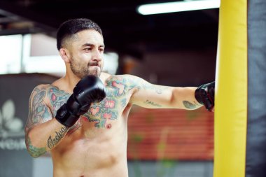 Dövmeli boksör antrenman sırasında yumruk atıyor.