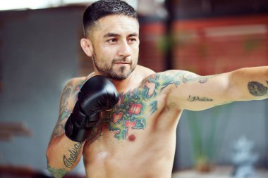 Dövmeli boksör antrenman sırasında yumruk atıyor.