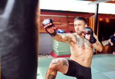 Bir spor salonunda güçlü vuruşlar yapmaya kararlı bir dövüşçü.