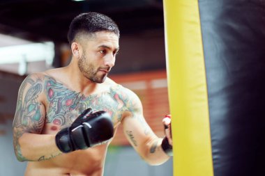 Spor salonunda boks eldiveni giyerek kum torbası eğitimi alıyor.