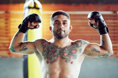 Kaslı İspanyol boksör boks eldiveni giyerken kaslarını ve dövmelerini gösteriyor.