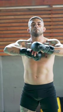 Dövmeli boksör spor salonunda poz verip kameraya bakıyor.