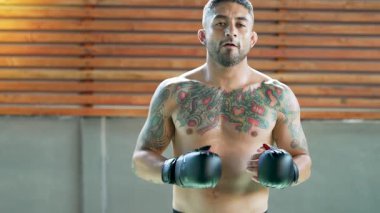 Dövmeli erkek boksör spor salonunda poz veriyor.