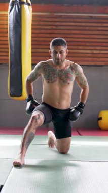 Dövmeli erkek boksör beden eğitimi öncesi esneme hareketleri yapıyor. 