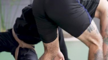 İki erkek sporcu jiu-jitsu çalışıyor, yakalama ve yer dövüşü teknikleri gösteriyor.