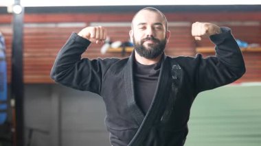 Kendine güvenen jiu-jitsu sporcusu spor salonunda kaslarını kasıyor.