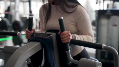 Latin Amerikalı kadın spor salonunda bir makine üzerinde egzersiz yapıyor, rutin yas tutuyor ve sağlıklı yaşam tarzı kavramı