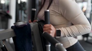 Latin Amerikalı kadın spor salonunda bir makine üzerinde egzersiz yapıyor, rutin yas tutuyor ve sağlıklı yaşam tarzı kavramı