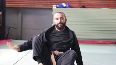 Kimonolu erkek sporcu spor salonunda jiu jitsu antrenmanına hazırlanıyor.