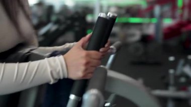 Latin Amerikalı kadın spor salonunda bir makine üzerinde egzersiz yapıyor, rutin yas tutuyor ve sağlıklı yaşam tarzı kavramı