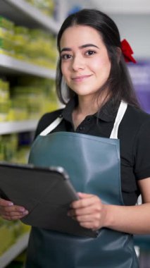 Küçük oto yedek parça mağazasında elinde dijital tablet tutan Latin Amerikalı satıcı.