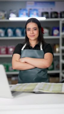 Latin Amerikalı genç bir kadın dizüstü bilgisayar kullanıyor ve küçük bir oto yedek parça şirketinde ürün listesine bakıyor.