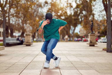 Latin Amerikalı break dansçı sokakta ayak hareketleri veya toprock yapıyor.