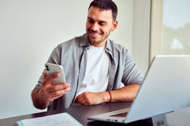Evdeki cep telefonu ve dizüstü bilgisayarını kullanarak işini yürüten mutlu girişimci