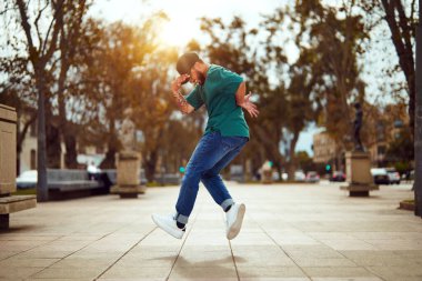 Latin Amerikalı break dansçı sokakta ayak hareketleri veya toprock yapıyor.