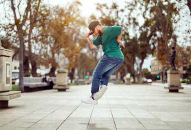 Latin Amerikalı break dansçı sokakta ayak hareketleri veya toprock yapıyor.