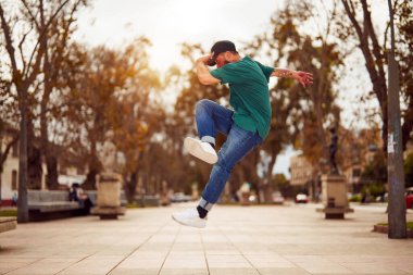 Latin Amerikalı break dansçı sokakta ayak hareketleri veya toprock yapıyor.