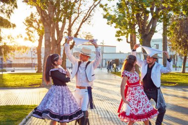 Şehir meydanında huaso gibi giyinmiş dört Latin Amerikalı genç dansçı grubu.