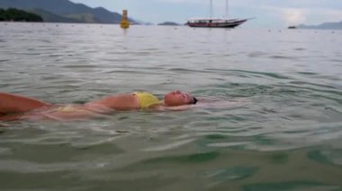 Sarı bikinili genç kadın denizde dinleniyor. 