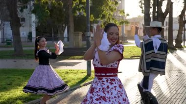 Geleneksel huaso kıyafetleri giymiş iki çiftin portresi şehir meydanındaki cueca ritmine alkış tutuyor.