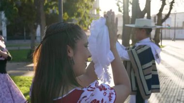 Geleneksel huaso kıyafetleri giymiş iki çiftin portresi şehir meydanındaki cueca ritmine alkış tutuyor.