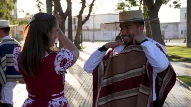 Geleneksel huaso kıyafetleri giymiş iki çiftin portresi şehir meydanındaki cueca ritmine alkış tutuyor.