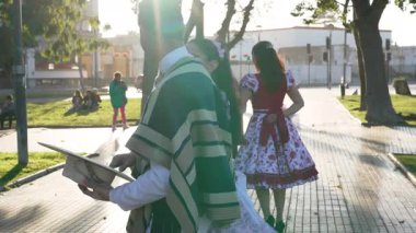 Şehir meydanında geleneksel huaso kıyafetleri içinde dans eden bir çiftin portresi.